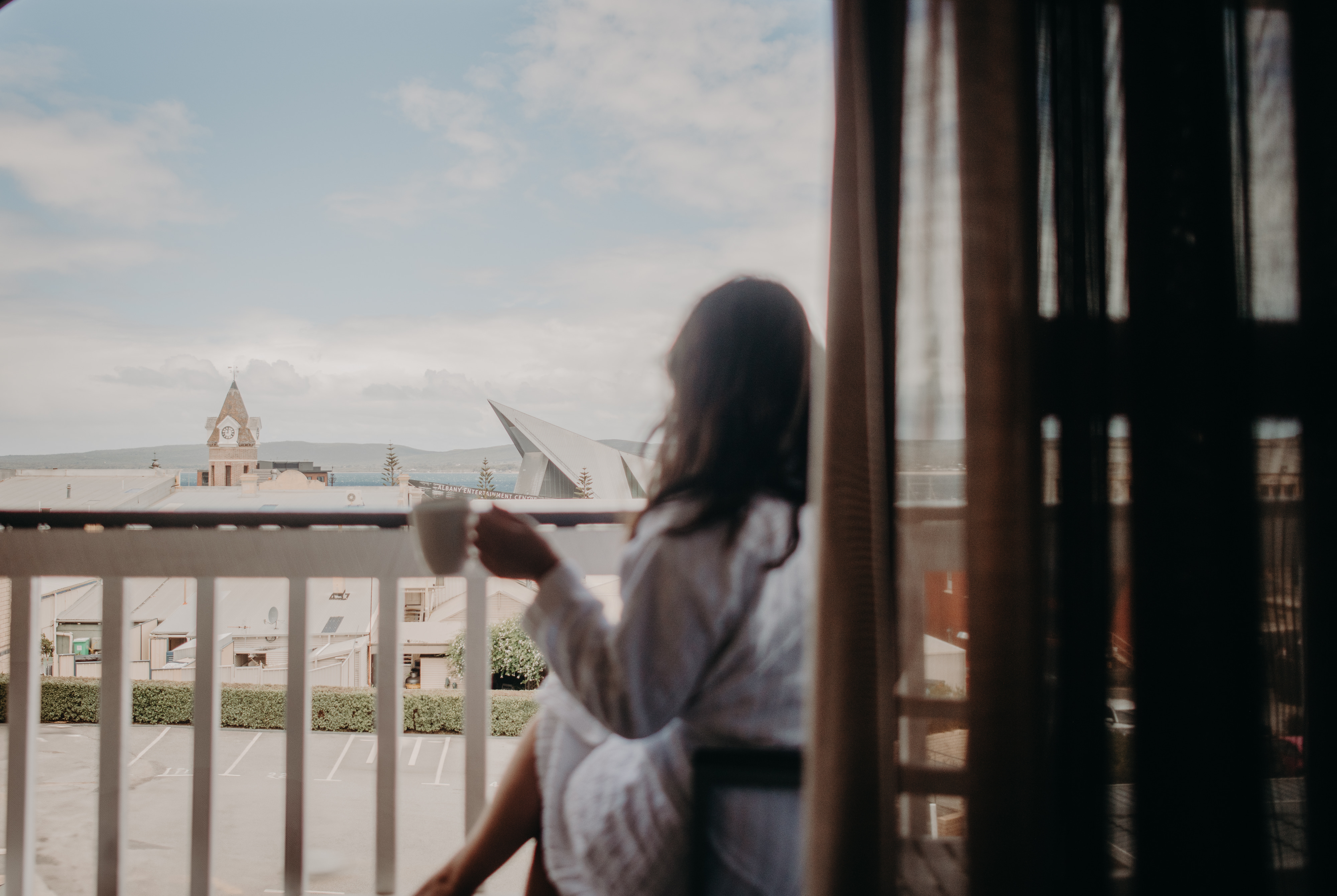 Guest enjoying coffee on a balcony at Albany Motel & Apartments, overlooking the Albany townscape